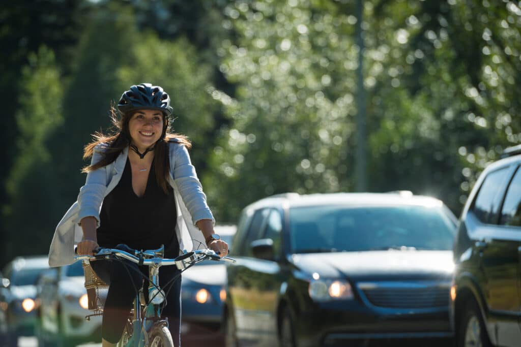 Young active woman riding a bike alongside a busy street