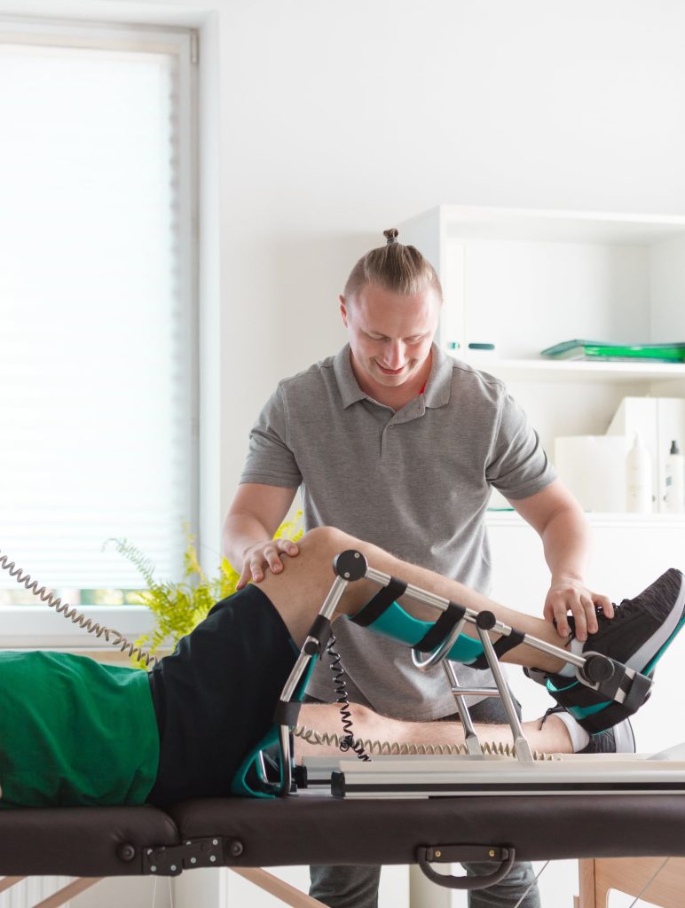 istock 1165861641 Physical therapist helping man lying on bed having rehabilitation of his knee with cpm machine after surgery