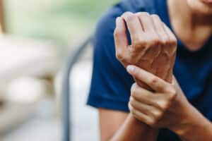Man holding his hand in pain from symptoms of Carpal Tunnel Syndrome or pinched nerve
