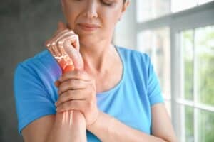 Woman holding her wrist in pain needing cortisone injections for relief in East Setauket, NY