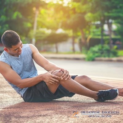 OALI LP (19) A man sitting on a track holding his knee and appearing to be in pain The logo “Orthopedic Associates of Long Island” is visible in the bottom right corner